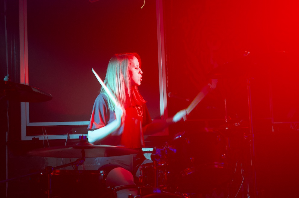 Bonnie Roe drumming with a red hue covering the image